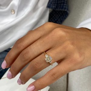 Emerald-cut three stone engagement ring with pear-shaped side stones and polished tapered band