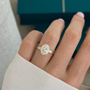 Elegant oval bezel engagement ring with baguette side stones and cathedral shoulders