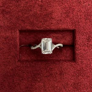 Emerald cut halo engagement ring with pavé shank, four prong setting